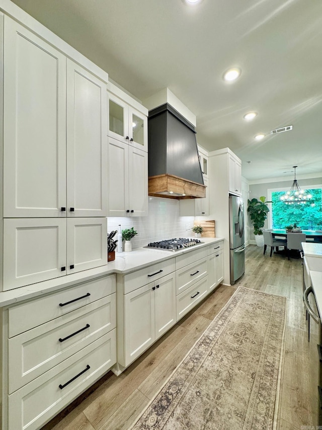 816 Nature Way, Benton, AR 72019 - kitchen with stainless steel appliances, custom exhaust hood, light wood-style floors, tasteful backsplash, and white cabinetry