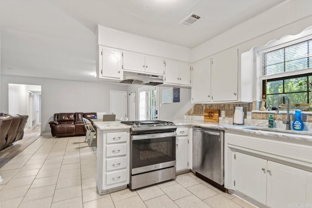 kitchen featuring appliances with stainless steel finishes, under cabinet range hood, a sink, open floor plan, and white cabinetry