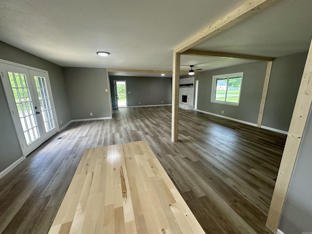 27 Grant 491 Rd, Sheridan, AR 72105 - unfurnished living room featuring plenty of natural light, baseboards, dark wood-type flooring, a ceiling fan, and beamed ceiling