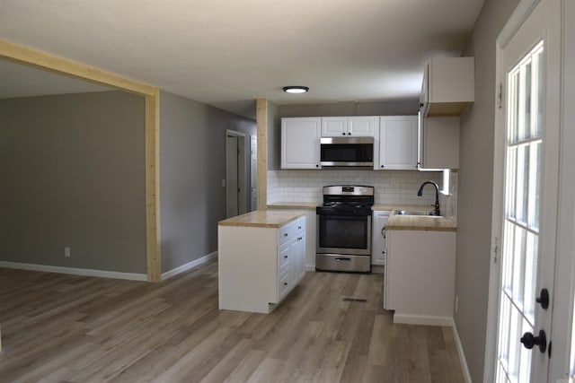 27 Grant 491 Rd, Sheridan, AR 72105 - kitchen featuring appliances with stainless steel finishes, a sink, tasteful backsplash, light wood finished floors, and white cabinetry