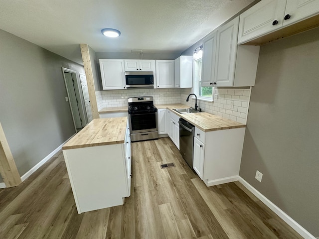 27 Grant 491 Rd, Sheridan, AR 72105 - kitchen with wooden counters, stainless steel appliances, a sink, light wood-type flooring, and a textured ceiling