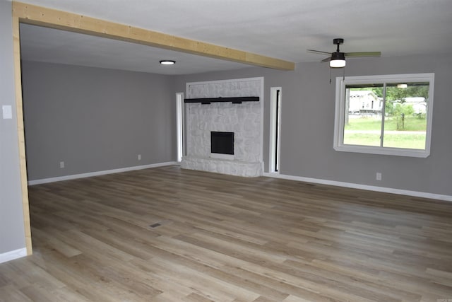 27 Grant 491 Rd, Sheridan, AR 72105 - unfurnished living room featuring wood finished floors, baseboards, a ceiling fan, beam ceiling, and a fireplace