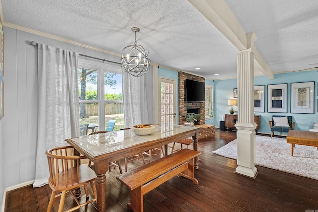 42 Desoto Cir, North Little Rock, AR 72116 - dining room with ornate columns, a textured ceiling, dark wood-style floors, a large fireplace, and a chandelier