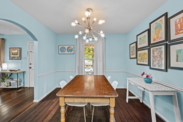 42 Desoto Cir, North Little Rock, AR 72116 - dining area featuring arched walkways, dark wood-style floors, a chandelier, a textured ceiling, and baseboards