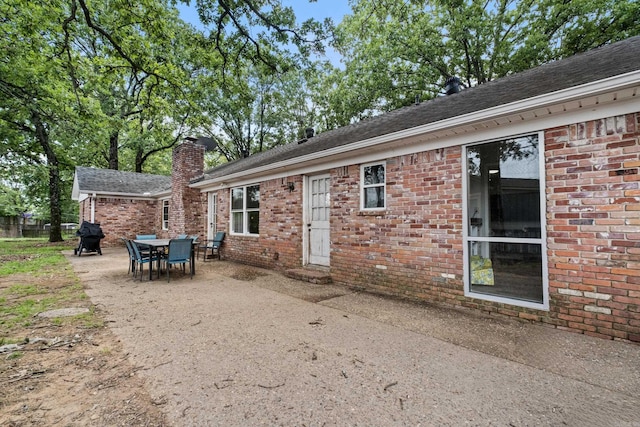 42 Desoto Cir, North Little Rock, AR 72116 - back of property featuring a patio, brick siding, a chimney, and roof with shingles