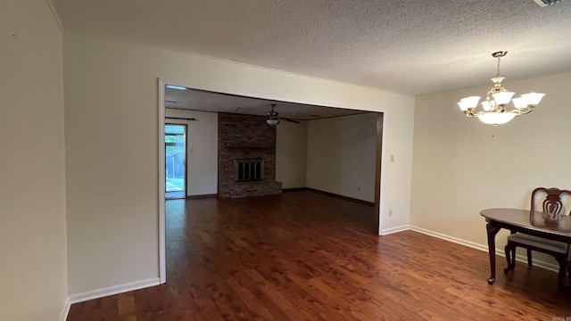 1410 Rock Creek Dr, Benton, AR 72019 - unfurnished living room with a chandelier, dark wood-type flooring, baseboards, a brick fireplace, and a textured ceiling