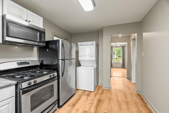 1724 W 19, Little Rock, AR 72202 - kitchen featuring stainless steel appliances, stacked washing machine and dryer, light wood-type flooring, white cabinetry, and light countertops