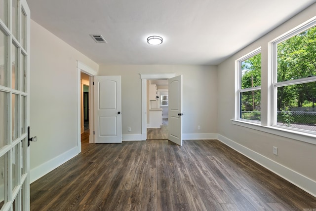 4300 W 16th St, Little Rock, AR 72204 - unfurnished bedroom with multiple windows, dark wood-type flooring, and baseboards