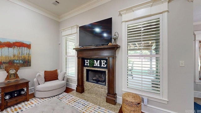 living area with a fireplace with flush hearth, crown molding, and baseboards