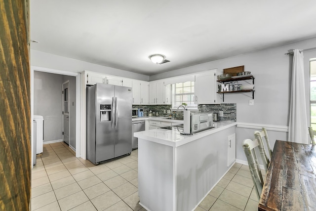 kitchen with stainless steel appliances, light tile patterned floors, a peninsula, decorative backsplash, and white cabinetry