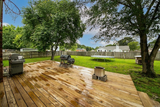 wooden terrace featuring a trampoline and area for grilling