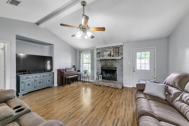 living room with light wood-type flooring, a ceiling fan, a fireplace, and baseboards
