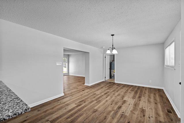 718 Coulter Rd, Sherwood, AR 72120 - unfurnished dining area featuring a chandelier, wood finished floors, water heater, a textured ceiling, and baseboards