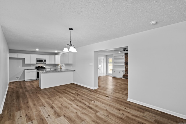 718 Coulter Rd, Sherwood, AR 72120 - kitchen featuring stainless steel appliances, open floor plan, dark wood-style flooring, a peninsula, and a textured ceiling