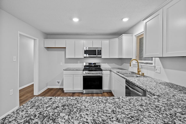718 Coulter Rd, Sherwood, AR 72120 - kitchen featuring appliances with stainless steel finishes, a sink, light stone countertops, dark wood-type flooring, and a textured ceiling