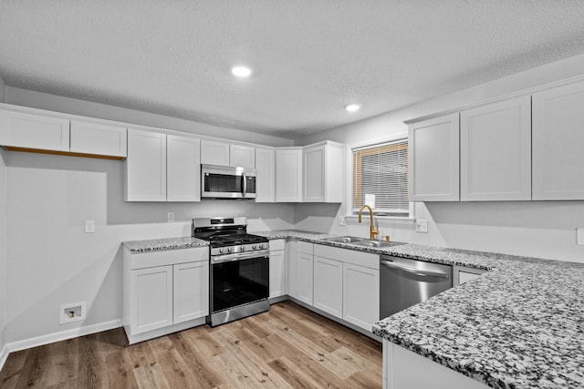 718 Coulter Rd, Sherwood, AR 72120 - kitchen featuring stainless steel appliances, a sink, a textured ceiling, white cabinetry, and light wood-style floors