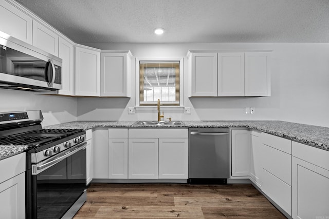 718 Coulter Rd, Sherwood, AR 72120 - kitchen with stainless steel appliances, a sink, a textured ceiling, white cabinets, and dark wood-type flooring