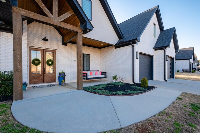 7021 Fields Dr, Alexander, AR 72019 - doorway to property featuring driveway, a garage, covered porch, french doors, and brick siding