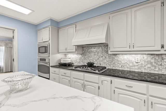 9 Leeward Ct, Maumelle, AR 72113 - kitchen featuring stainless steel appliances, premium range hood, decorative backsplash, dark stone counters, and a textured ceiling
