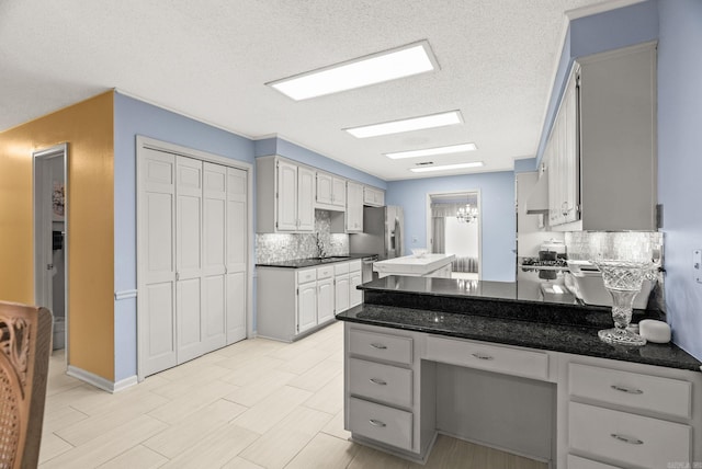 9 Leeward Ct, Maumelle, AR 72113 - kitchen featuring tasteful backsplash, a textured ceiling, a peninsula, a sink, and stainless steel fridge with ice dispenser
