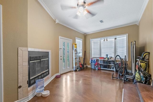 1217 Look St, Little Rock, AR 72204 - workout room with crown molding, ceiling fan, baseboards, a tiled fireplace, and a textured ceiling