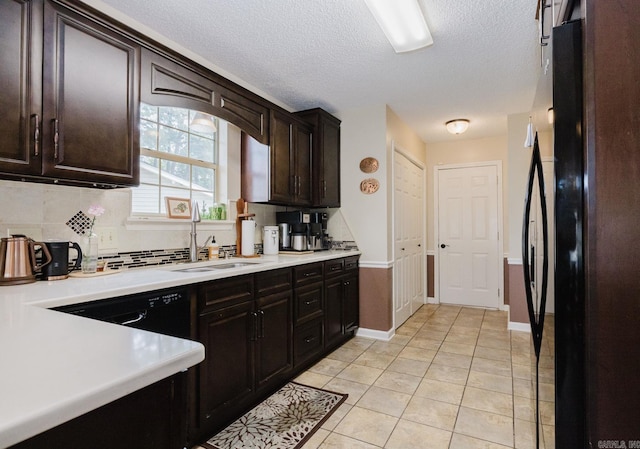 kitchen featuring freestanding refrigerator, a sink, decorative backsplash, a textured ceiling, and light countertops