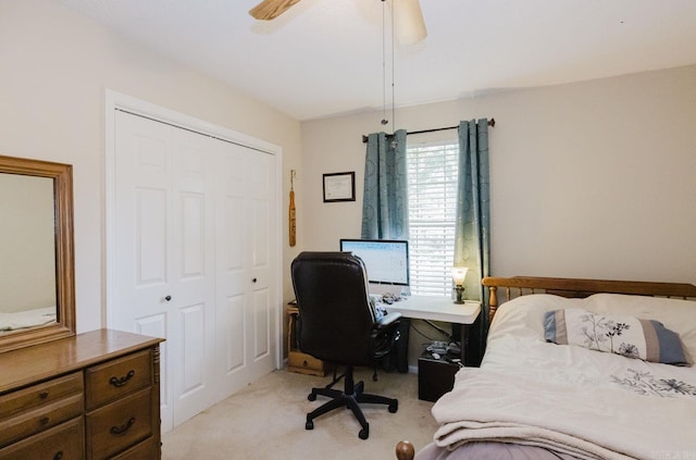 bedroom featuring a closet, light carpet, an office area, and ceiling fan