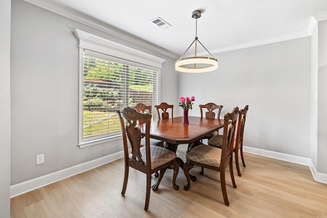 dining area featuring ornamental molding, light wood-style floors, and baseboards