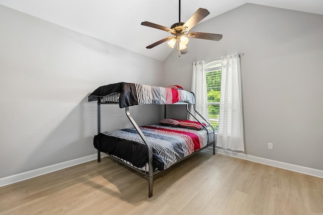 bedroom with vaulted ceiling, wood finished floors, baseboards, and a ceiling fan