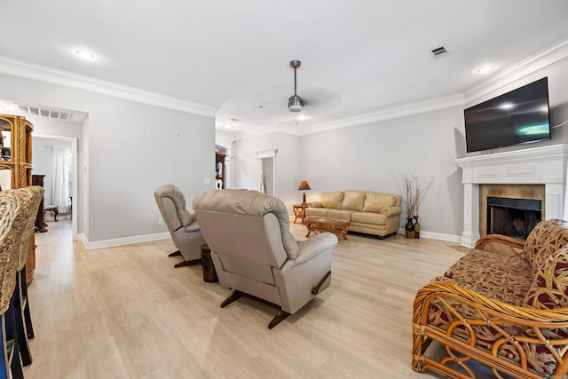 living area with a fireplace, light wood finished floors, baseboards, crown molding, and ceiling fan