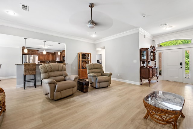 living area featuring baseboards, light wood-style flooring, ceiling fan, and ornamental molding