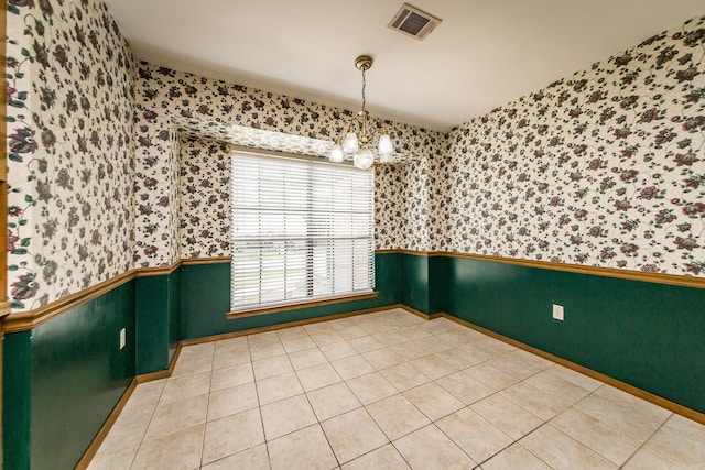 unfurnished dining area featuring wallpapered walls, a wainscoted wall, a chandelier, baseboards, and light tile patterned floors