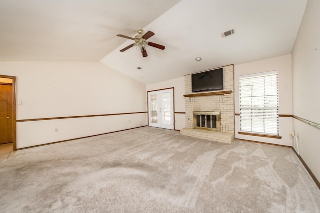 unfurnished living room with ceiling fan, vaulted ceiling, plenty of natural light, a fireplace, and carpet