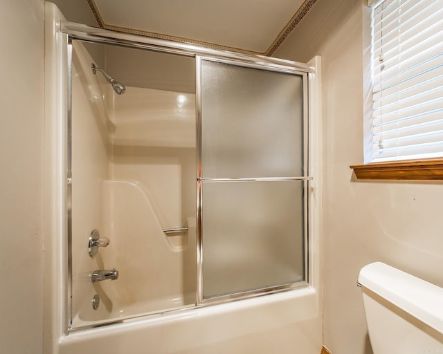bathroom featuring toilet and combined bath / shower with glass door