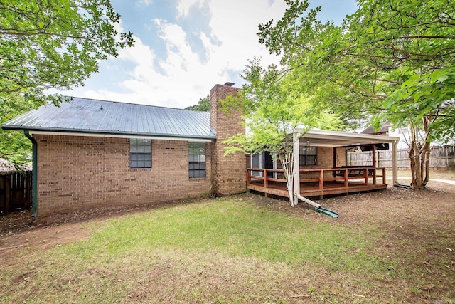 rear view of property with a chimney, a wooden deck, brick siding, and metal roof
