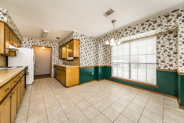 kitchen with wallpapered walls, a sink, range with electric stovetop, light countertops, and healthy amount of natural light