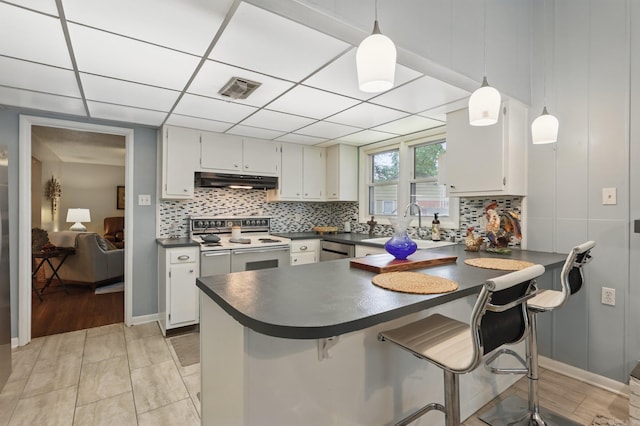 717 Choctaw Cir, Little Rock, AR 72205 - kitchen with range with two ovens, dark countertops, under cabinet range hood, a peninsula, and backsplash