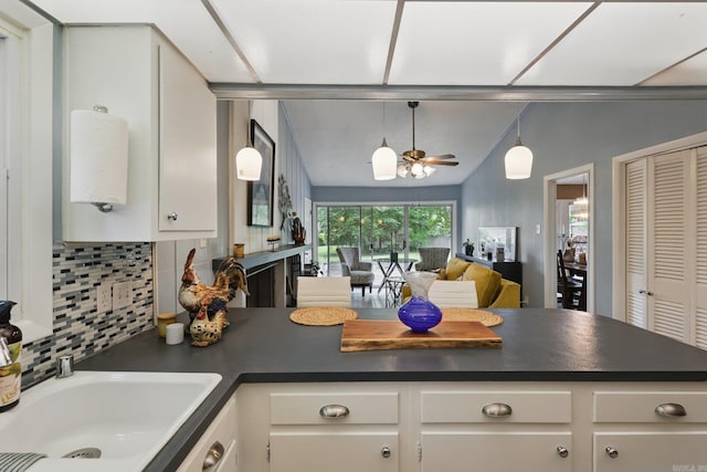 717 Choctaw Cir, Little Rock, AR 72205 - kitchen with dark countertops, a sink, backsplash, white cabinetry, and open floor plan