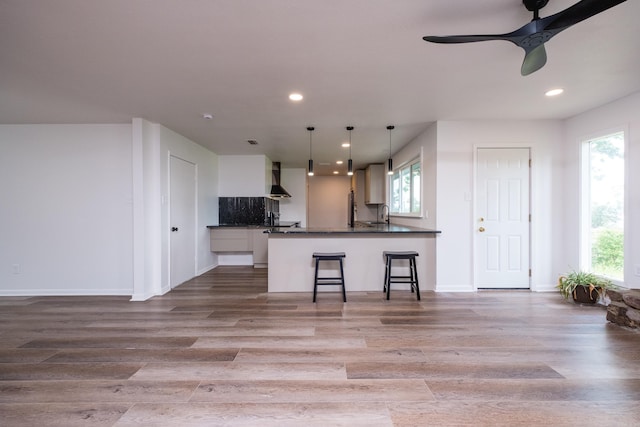 1117 Wild Turkey Ct, Little Rock, AR 72211 - kitchen featuring dark countertops, wall chimney exhaust hood, light wood-style flooring, recessed lighting, and white cabinets