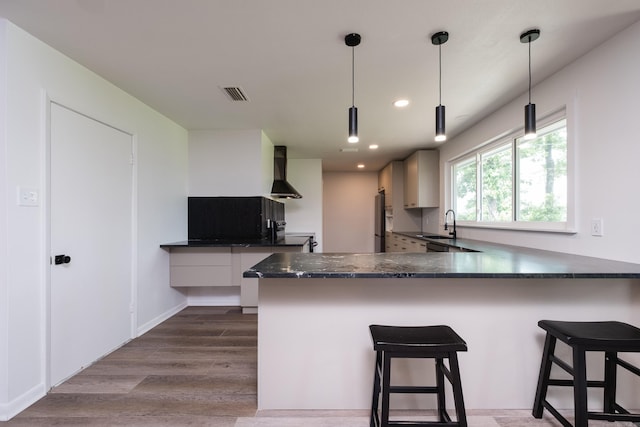 1117 Wild Turkey Ct, Little Rock, AR 72211 - kitchen featuring wall chimney exhaust hood, freestanding refrigerator, a breakfast bar area, dark wood-style flooring, and recessed lighting