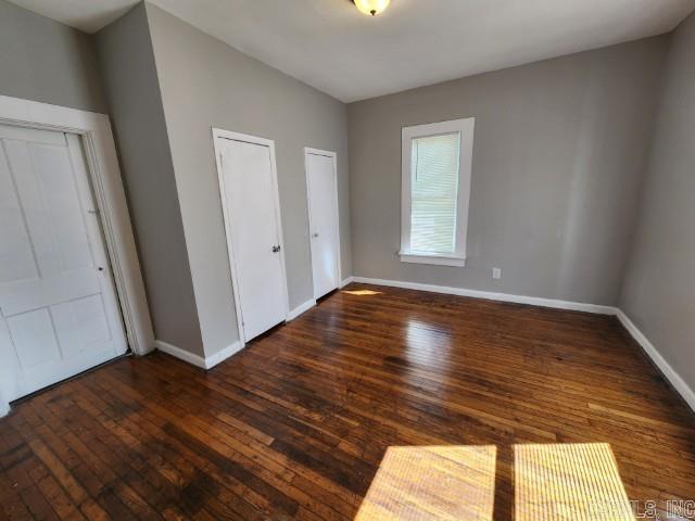 3716 Marion St, North Little Rock, AR 72118 - unfurnished bedroom with wood-type flooring, baseboards, and multiple closets
