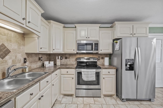 kitchen featuring stainless steel appliances, a sink, decorative backsplash, dark countertops, and a textured ceiling