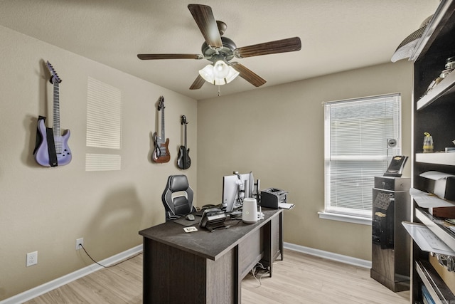 home office with light wood-style flooring, a ceiling fan, and baseboards