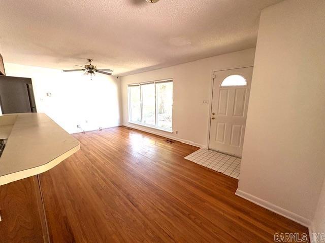 4900 Lochridge Rd, North Little Rock, AR 72116 - unfurnished living room featuring wood finished floors, a ceiling fan, baseboards, and a textured ceiling