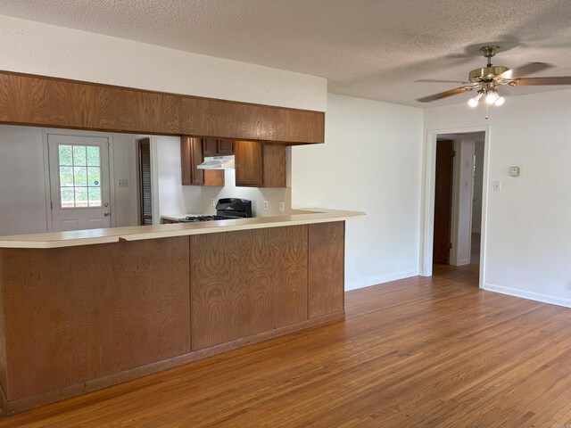 4900 Lochridge Rd, North Little Rock, AR 72116 - kitchen featuring under cabinet range hood, gas stove, wood finished floors, a peninsula, and light countertops