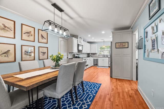 3016 Cleburne Pl, North Little Rock, AR 72116 - dining area featuring wine cooler, light wood finished floors, recessed lighting, crown molding, and baseboards