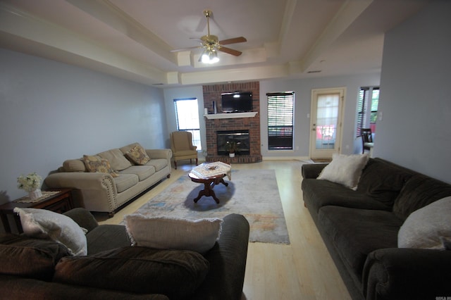 12601 Woodbury Dr, Little Rock, AR 72211 - living area with a raised ceiling, light wood-style floors, a ceiling fan, and a brick fireplace