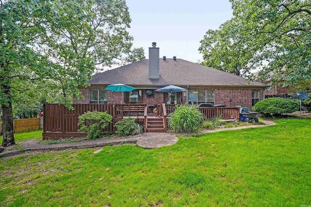 back of house with brick siding, a chimney, a lawn, and a deck