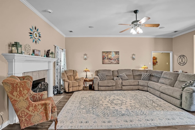 living area featuring ornamental molding, wood finished floors, ceiling fan, and a fireplace