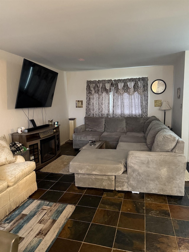 living area with stone finish floors and a glass covered fireplace